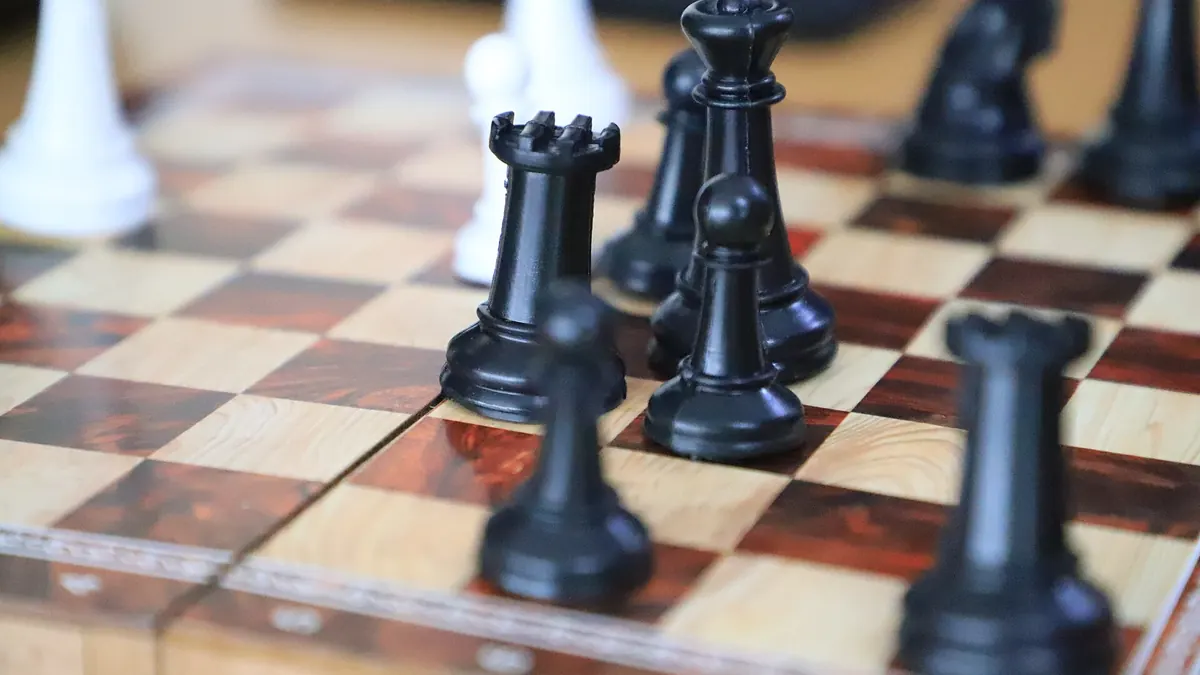 Black chess pieces on a wooden chessboard
