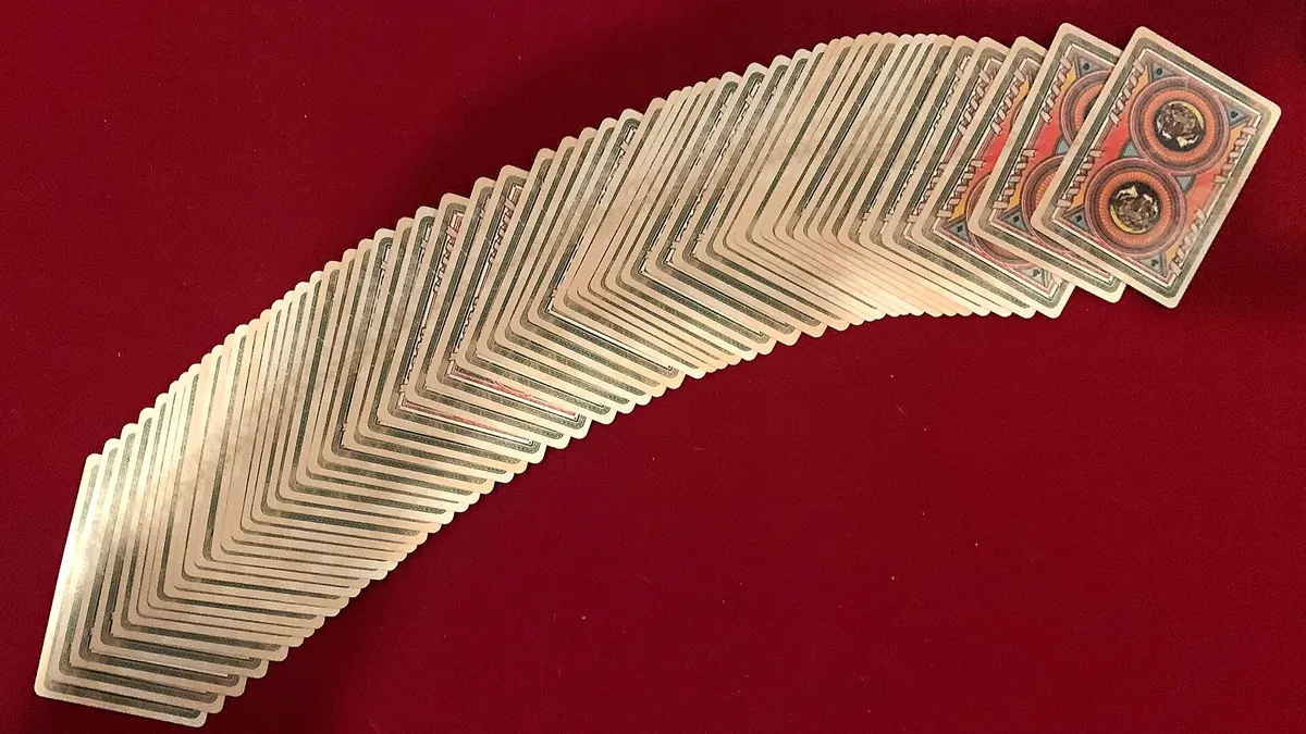 A deck of playing cards spread in an arc on red cloth