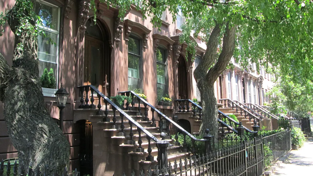 Brownstone row houses with stoops on a tree-lined Brooklyn street